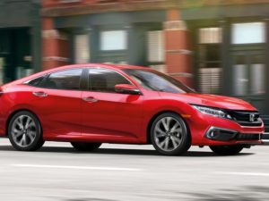 A red honda civic driving on an urban street, captured with motion blur.