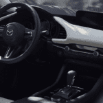 A car is shown with the dashboard and steering wheel.