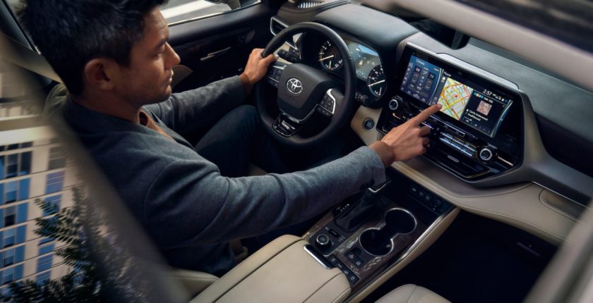 A man in the driver 's seat of a car looking at an ipad.