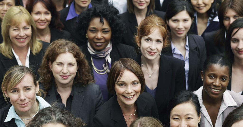 A group of women in business attire smiling for the camera.