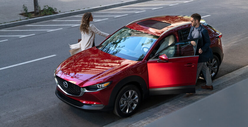 A woman is standing next to a red car.
