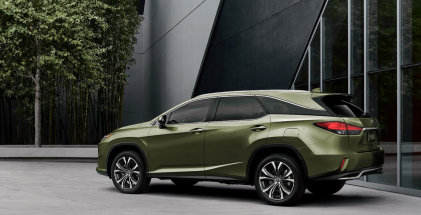 A green lexus suv parked in front of a building.