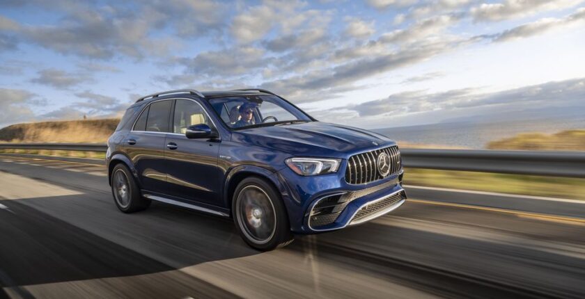 A blue mercedes benz suv driving down the road.