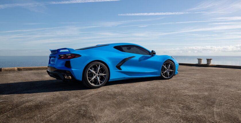 A blue sports car parked on top of a dirt field.