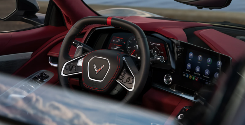 A steering wheel and dashboard of a red car.