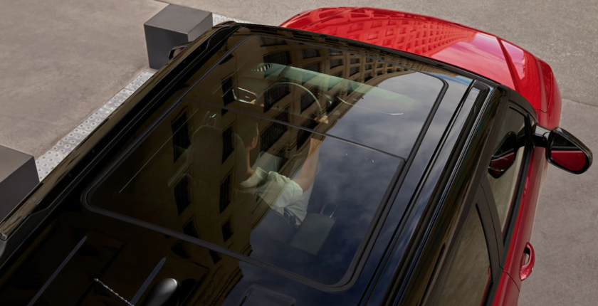 A person is reflected in the window of a car.