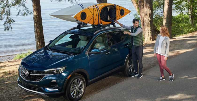 A man standing next to his car with a kayak on the roof.