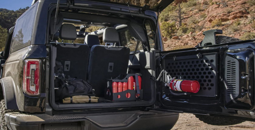 A jeep with the doors open and its trunk filled with items.