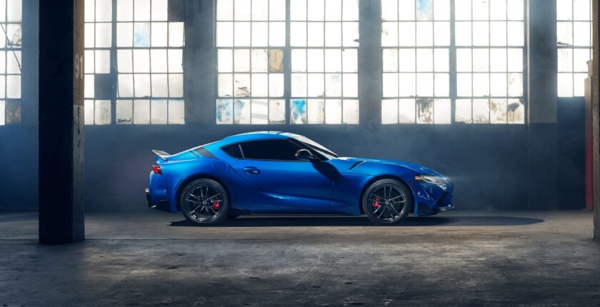 A blue sports car parked in front of a large window.