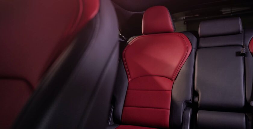 A red car seat in the middle of a room.