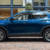 A blue car parked on the side of a brick road.