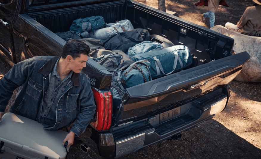 A man sitting in the back of his truck with luggage.