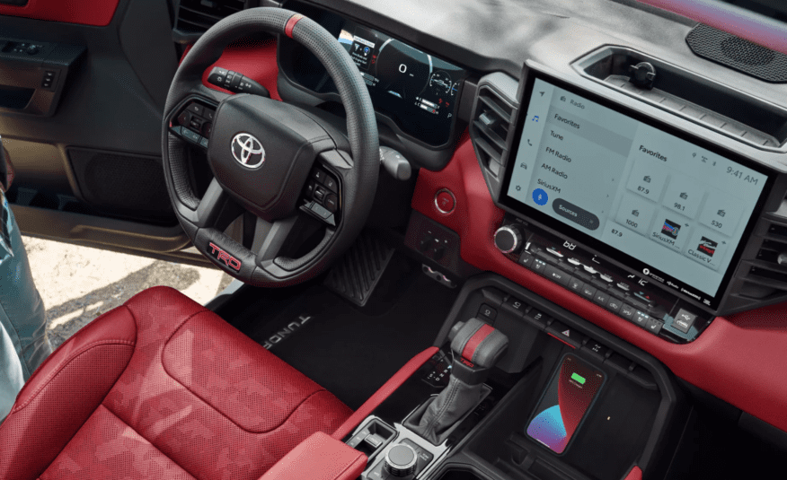 A red car with the steering wheel and dashboard in view.