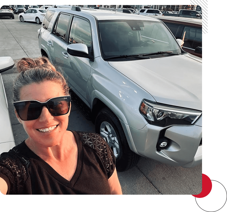 A woman standing in front of a silver truck.