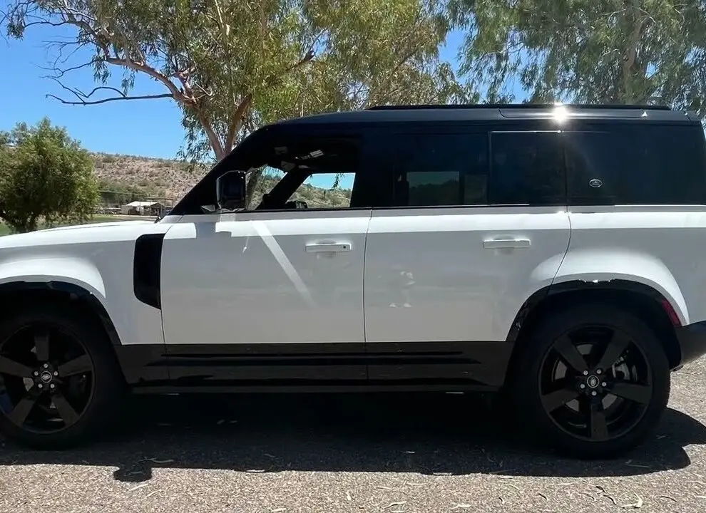 A white land rover parked on top of a dirt road.