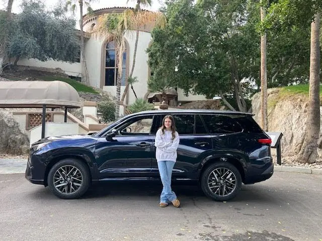 A woman standing next to a black suv.